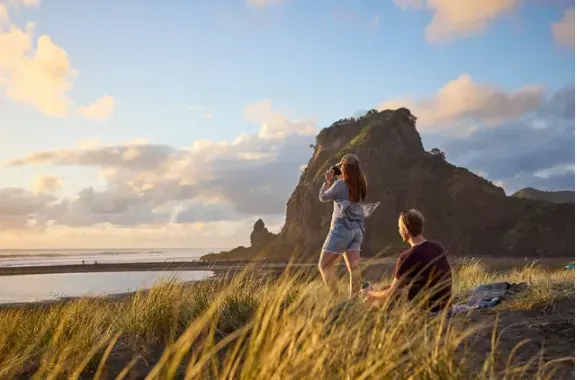 People sitting on the top of a sand dune looking out over the ocean