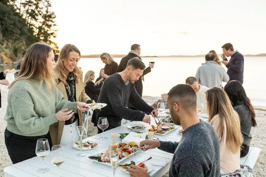 People sitting around a table near a beach enjoying a meal